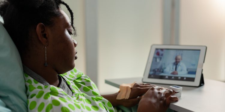 African american sick young patient resting in bed discussing healthcare treatment with remote physician doctor during online videocall meeting conference. Telehealth call on tablet screen