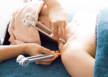 Woman recieving aroma tuning fork therapy on her neck.