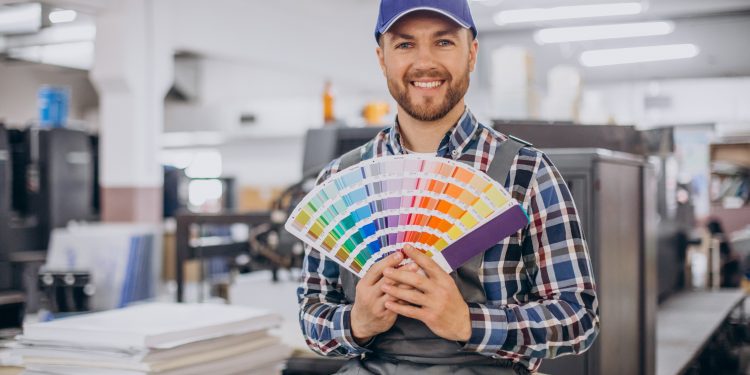 Man working in printing house with paper and paints