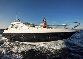 A person enjoying a sunny day on a sleek yacht cruising through blue waters.