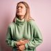 Young beautiful blonde woman wearing winter wool sweater over pink isolated background with hand on stomach because nausea, painful disease feeling unwell. Ache concept.