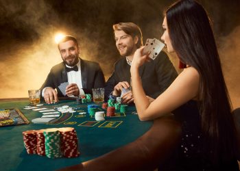 Group of young rich people is playing poker in the casino. Two men in business suits and a young woman in a black dress. Smoke. Casino. Poker