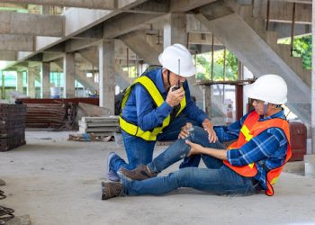 Asian factory workers having accident while working in manufacturing site while his colleague is helping for safety workplace and emergency