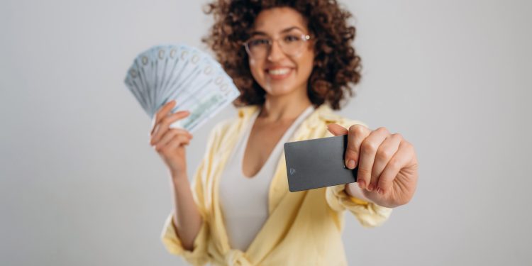 Lot of money and credit card in hands. Beautiful woman is in the studio.