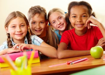 Portrait of smart schoolchildren looking at camera in classroom