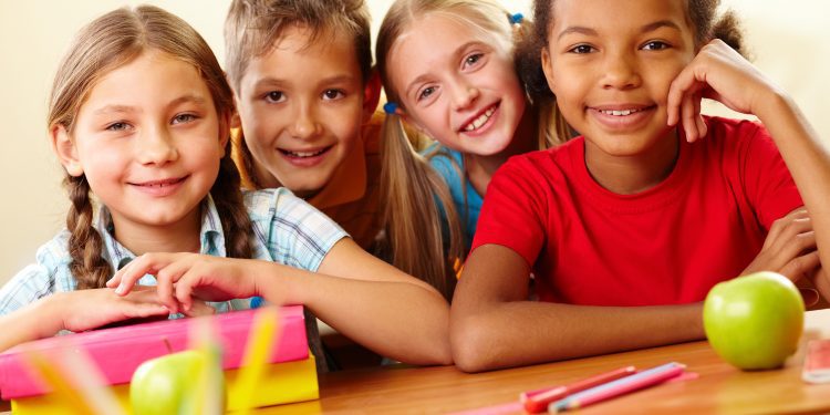 Portrait of smart schoolchildren looking at camera in classroom