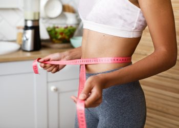 African woman is measuring her waist with a centimeter