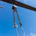Close-up of a metal chain of a crane lifted up against a clear blue sky at a construction site in working condition for lifting and transporting a heavy load.