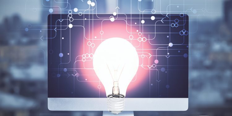 Computer on desktop in office with bulb icon hologram. Multi exposure. Concept of idea.