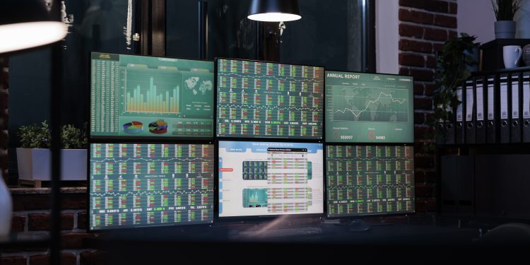 Empty interior of forex market exchange company office with financial data and growth charts on multiple displays. Workspace equipped with workstation having finance statistics and real time graph.