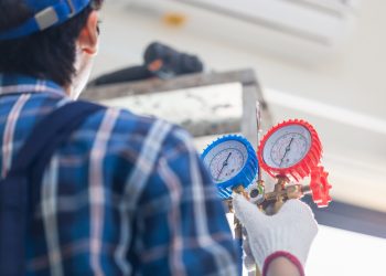 Rear view of Technician man fixing air conditioner unit, Repairman installing air conditioning in a client house, Maintenance and repairing concepts