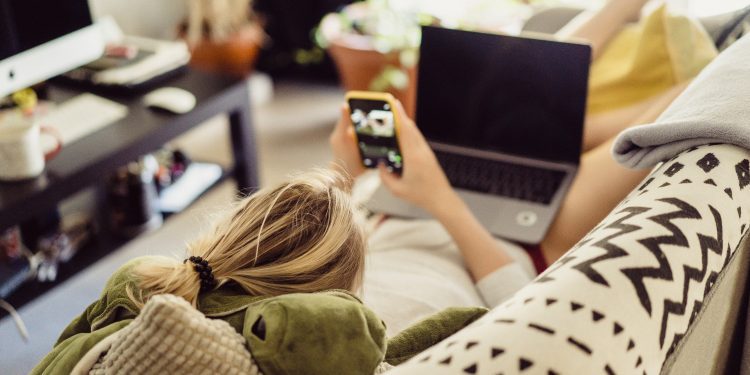 woman lies on a sofa with a laptop. Leisure on isolation. Working on a laptop from home.