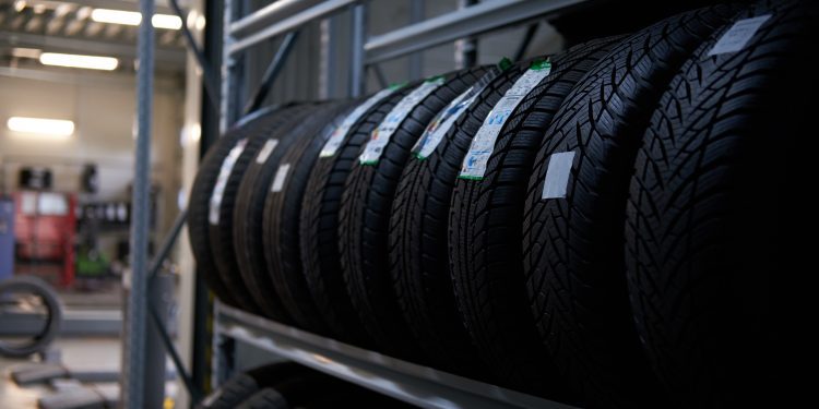 Brand new big variety of car's tyres on shelf with prices at store or warehouse.