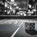A close-up image of a dice on a craps table in a casino, with a blurry background of lights and a casino floor. This photo captures the thrill and excitement of gambling, with a sense of mystery and chance.