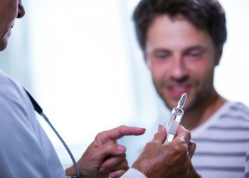 Doctor showing injection to patient in hospital