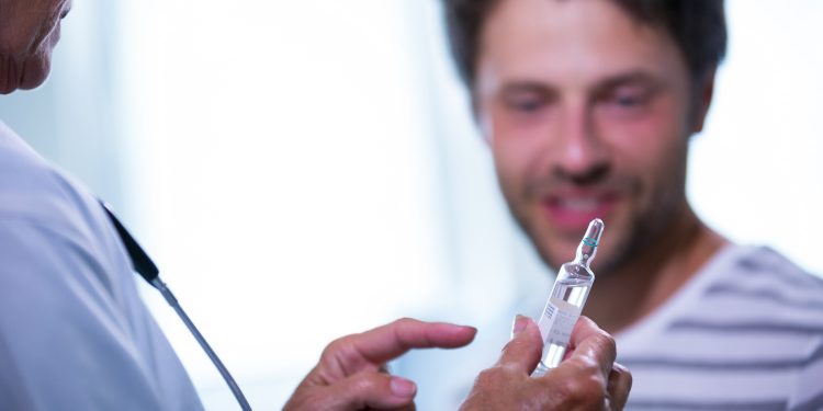 Doctor showing injection to patient in hospital
