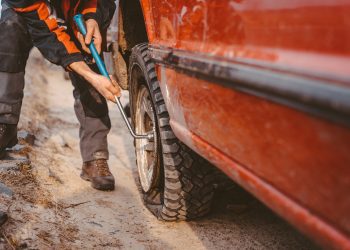 Man changes the wheel manually on a 4x4 off road truck on the road