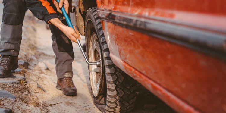 Man changes the wheel manually on a 4x4 off road truck on the road