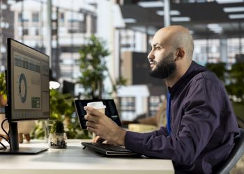 Middle eastern office employee working with monthly revenue balance to create financial plans using online tools, reviewing data analytics. Young businessman manages objectives for success.