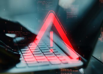Red exclamation warning symbol overlaying a laptop keyboard with programming code in the background. Concept of software error or digital issue