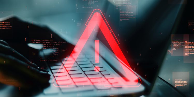 Red exclamation warning symbol overlaying a laptop keyboard with programming code in the background. Concept of software error or digital issue