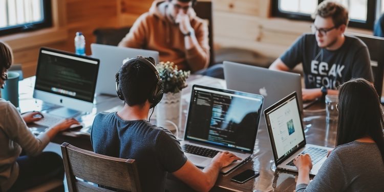 Team of IT specialists working on laptops in modern office.