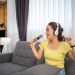 Woman wearing headphones and listening to music and singing happy at home on vacation.