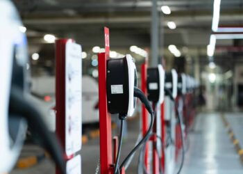 Electric car charging station for charge EV battery. Plug for vehicle with electric engine. EV charger. Clean energy. Charging point at car parking lot. Green power. Future transport technology.