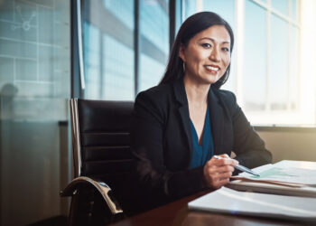 Asian woman, portrait and documents with charts, smile and review for financial data at agency. Risk analyst, person or happy with paperwork, stats or info on graphs for business growth in Jakarta.