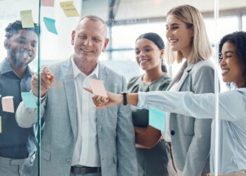 Business people planning on sticky note in meeting, post it paper for creative advertising idea and team collaboration for marketing project. Teamwork for global company strategy on glass in office.