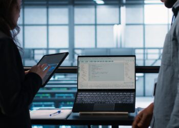 Programmers using AI technology on laptop and tablet in data center employing machine learning models. Devices used by artificial intelligence IT experts in server farm, camera A