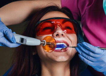 Female dentist treating a patient. Close-up photo of a young woman sitting in the dentist's chair.