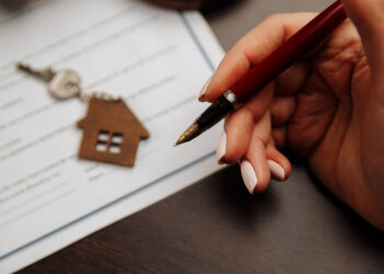 House keys and money on a signed contract of house sale. Focus on keys.