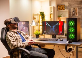 Professional gamer man using VR headset to play on powerful PC late at night in his living room