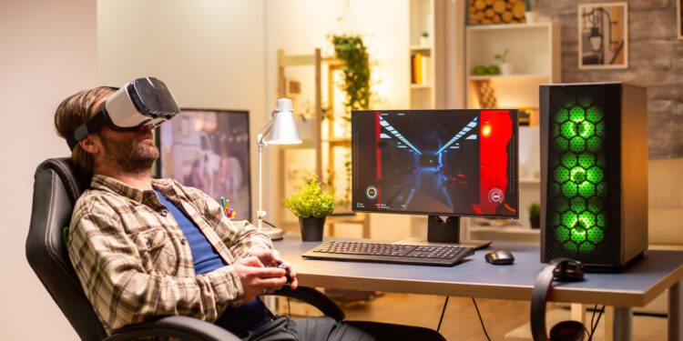 Professional gamer man using VR headset to play on powerful PC late at night in his living room