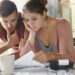 Young female and her unemployed husband with many debts doing paperwork together in kitchen, reading notification, informing that they must move out from their apartment because of non-payment