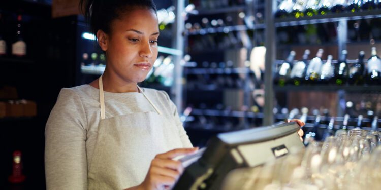 Pretty young cashier registrating orders of clients of cafe, bar or restaurant