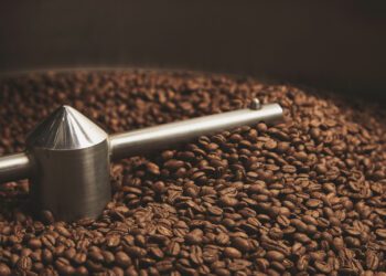 Dark, aromatic, chocolate coffee beans freshly baked and hot cool dawn inside the best professional roasting machine close up focus