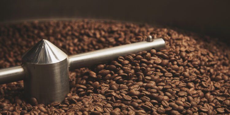 Dark, aromatic, chocolate coffee beans freshly baked and hot cool dawn inside the best professional roasting machine close up focus