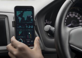 Driver checking stock market on his phone while in the car
