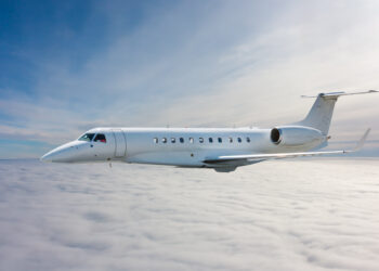 White modern luxury private jet flies in the air above the clouds