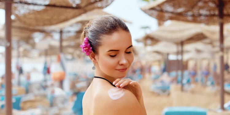 Woman smile applying sunscreen on  tanned  shoulder. Skincare. Body Sun protection sun cream. Bikini  woman smear  moisturizing lotion on back