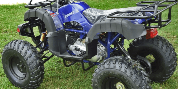 Blue ATV parked on green grass.