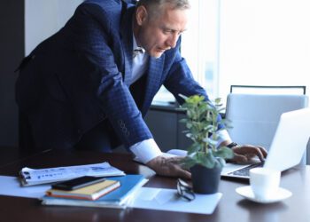 Elegant mature businessman analyzing data while working in office