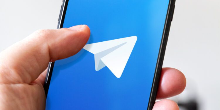 Paris - France - March 23, 2021 : Hand holding iphone smartphone with Telegram logo