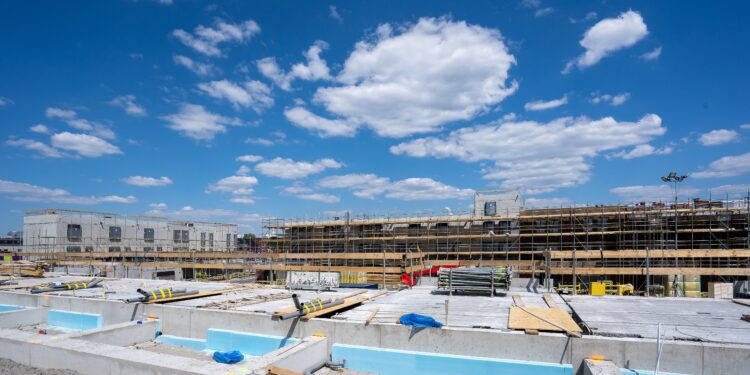 A horizontal shot of a construction site with scaffolding under the clear blue sky