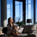 Side view of smiling beautiful brunette woman sitting on cozy grey sofa and near large panoramic window. Concept of enjoying free time at home with modern interior.