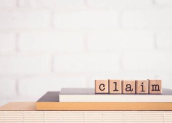 The word CLAIM, alphabets on wooden rubber stamps on top of books with bricks background, blank copy space, vintage minimal style. Concepts of compensation, legal policy and business insurance.