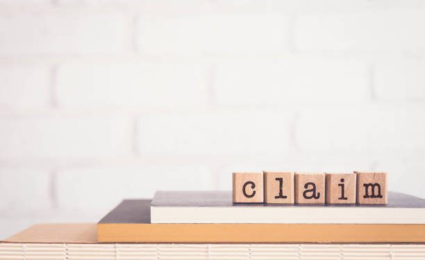 The word CLAIM, alphabets on wooden rubber stamps on top of books with bricks background, blank copy space, vintage minimal style. Concepts of compensation, legal policy and business insurance.