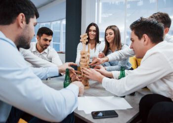 It's almost fall of. Celebrating successful deal. Young office workers sitting near the table with alcohol.